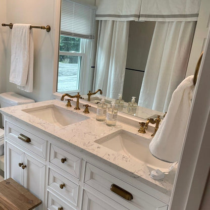 White double-sink vanity with gold hardware and white towel