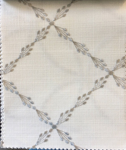 Fabric close-up showing silver embroidered sprigs on white linen weave