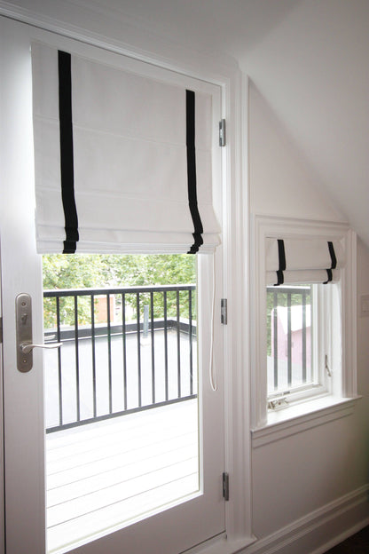 Aran flat Roman shade with black border on a French door and window