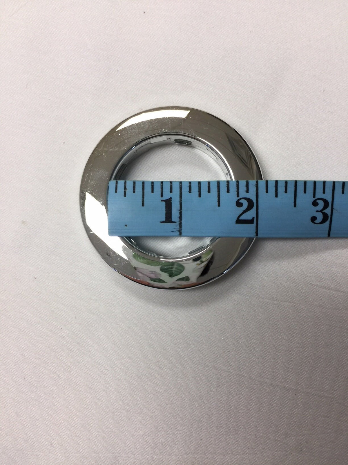 Silver grommet shown against a tape measure for scale