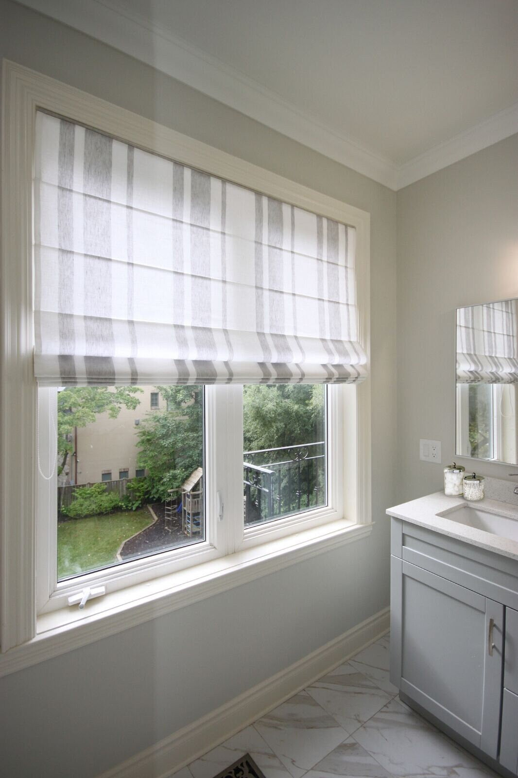 Flat Roman shade in white linen with grey stripes on a bathroom window — LOGANOVA