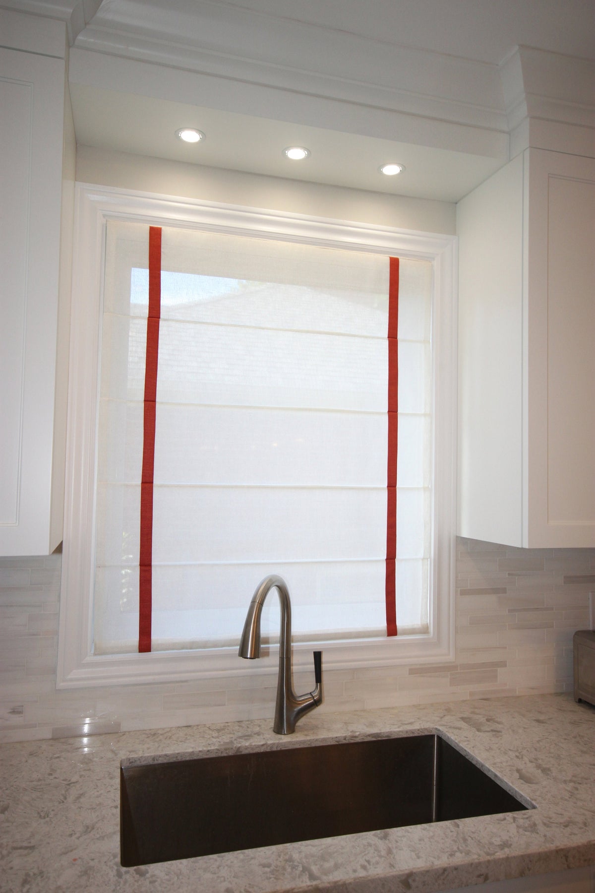 Champagne sheer Roman shade with red grosgrain border