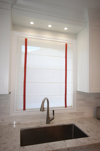 Champagne sheer Roman shade with red grosgrain border