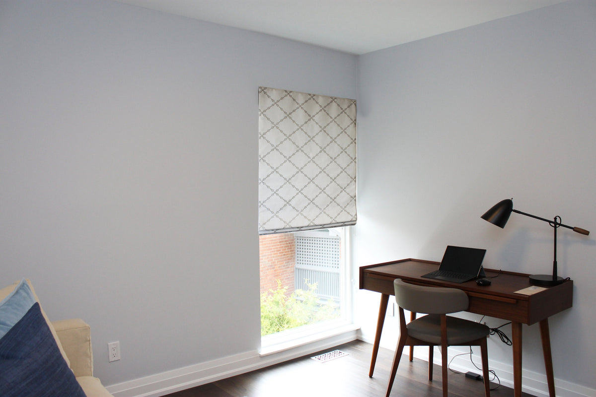 Window in a home office dressed with the patterned Ryder Silver relaxed Roman shade