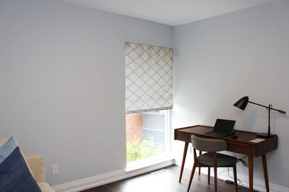 Window in a home office dressed with the patterned Ryder Silver relaxed Roman shade