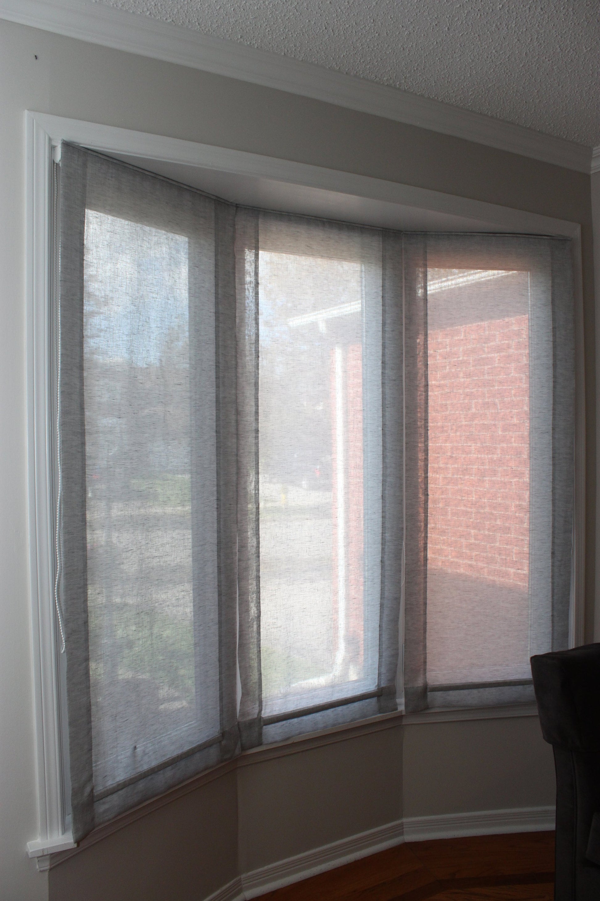 Three Utopia sheer linen relaxed Roman shades fitted on a bay window — LOGANOVA