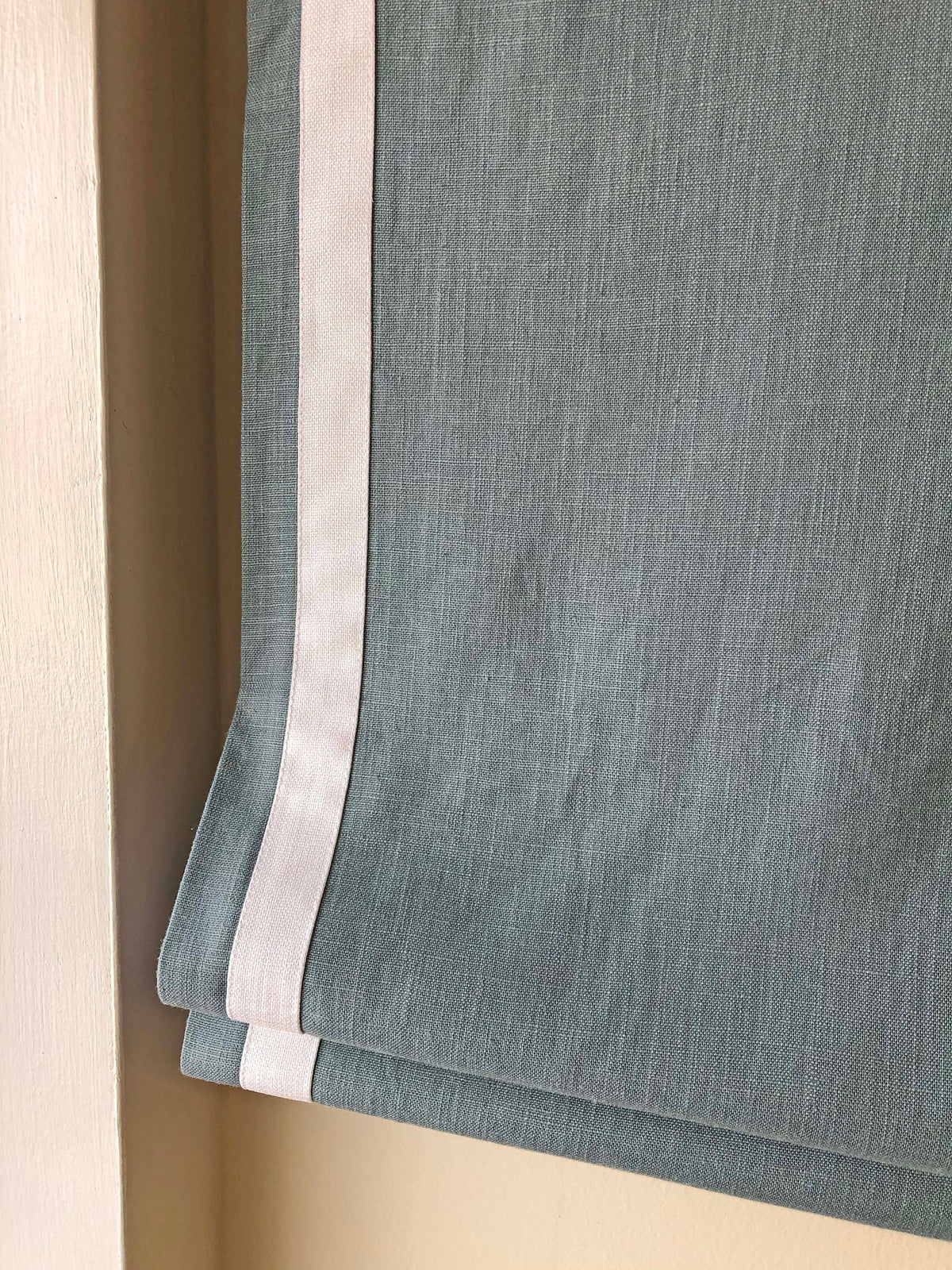 White border trim running down both vertical sides of the Roman shade