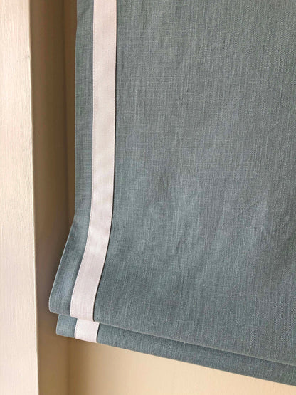 White border trim running down both vertical sides of the Roman shade