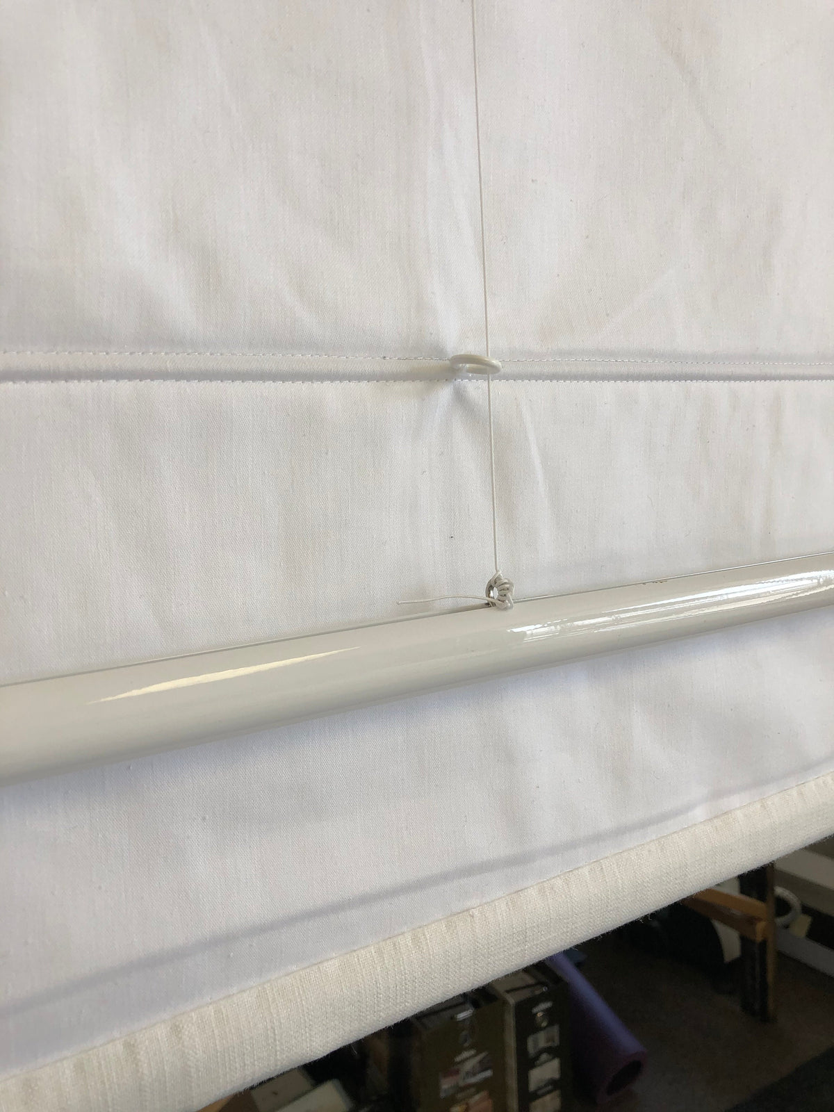 Back of a white Roman shade showing the premium lining and weighted bottom bar