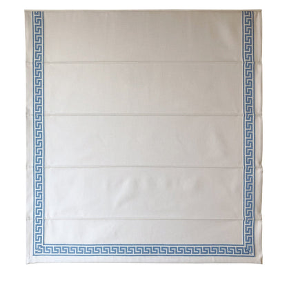 Close view of the blue Greek key trim along the hem of a white Roman shade