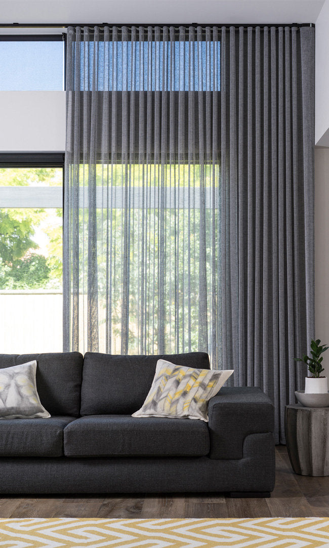 Smoke grey Berlin s-fold sheers filtering light behind a sofa — LOGANOVA