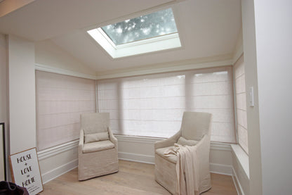 Relaxed linen Roman shades in a skylit sitting room with a slipcovered armchair