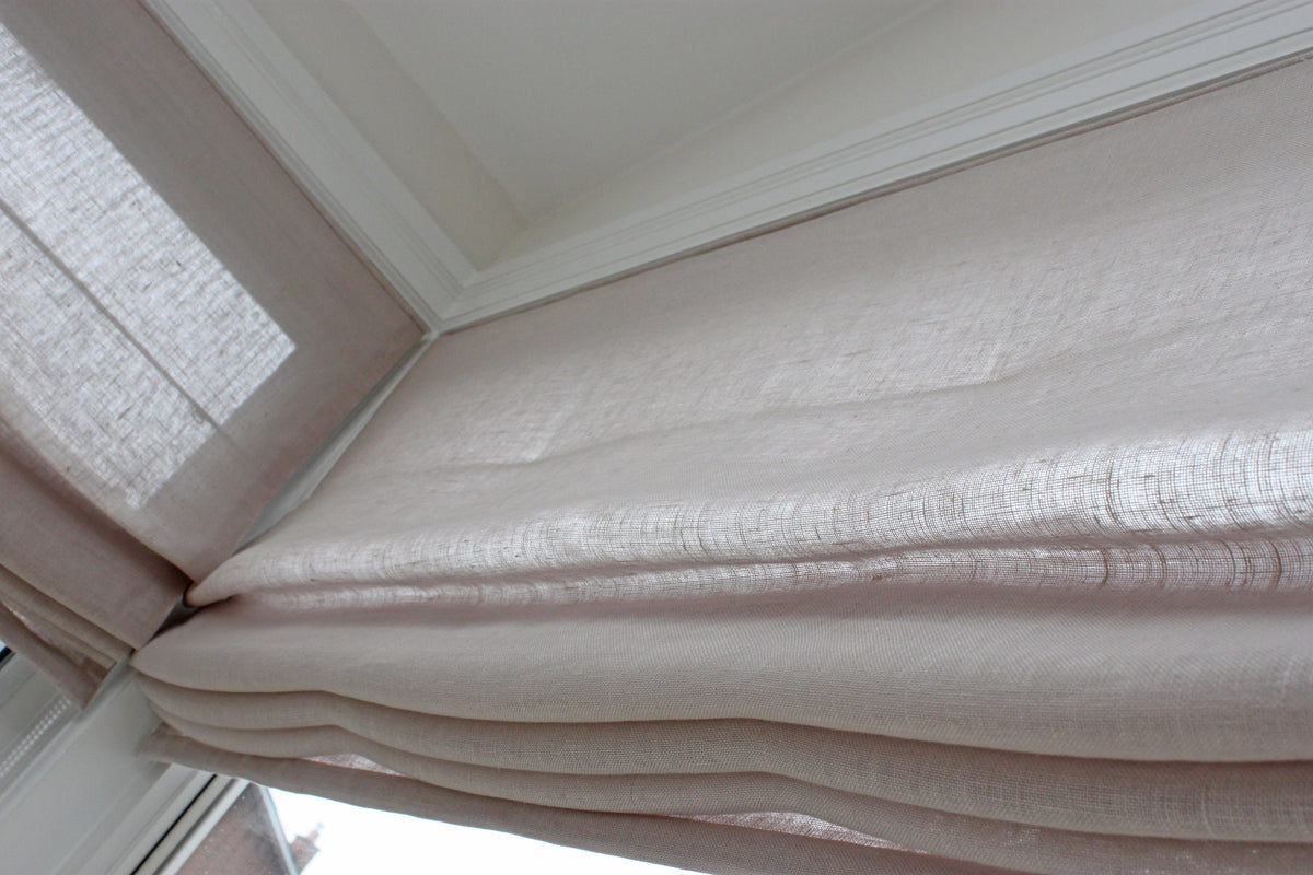 Detail of the header and stacked folds on a made to order linen Roman shade