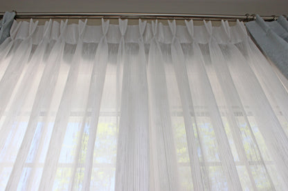 Lugano pinch pleat sheer drapery panel hanging at a window