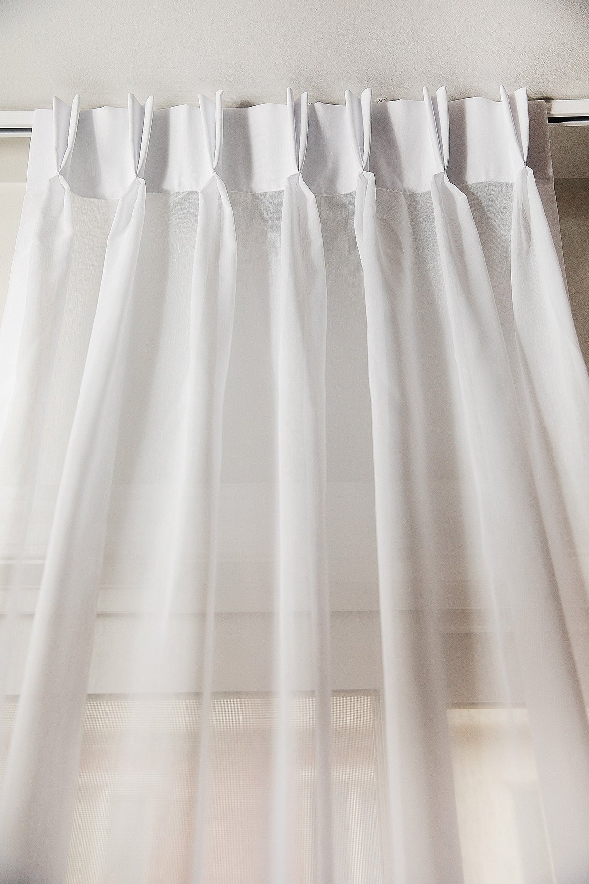 Dallas sheer double pleat drapery panel in white, hung on a track