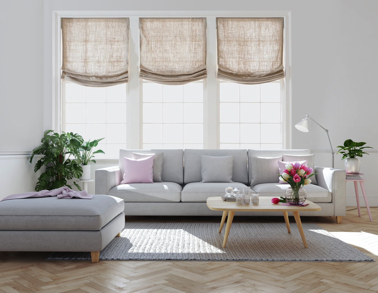 Three linen European relaxed Roman shades over a grey sofa in a bright living room with herringbone floor