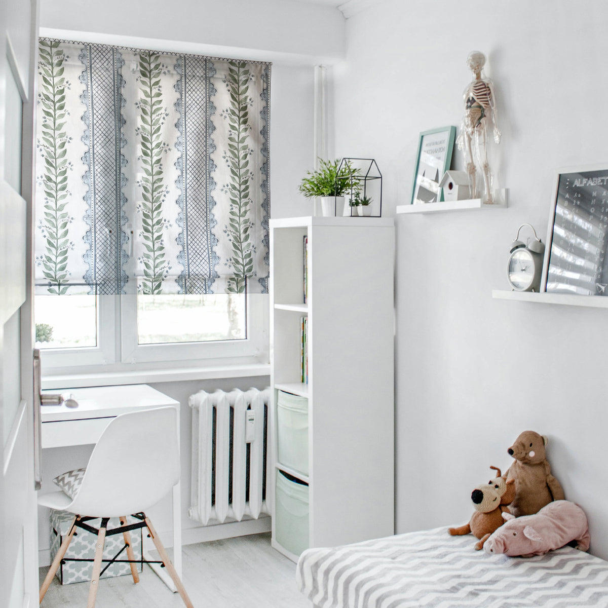 Celia Quiet Blue on Cream relaxed Roman shade in a white child's bedroom with desk, bookshelf and striped bedspread