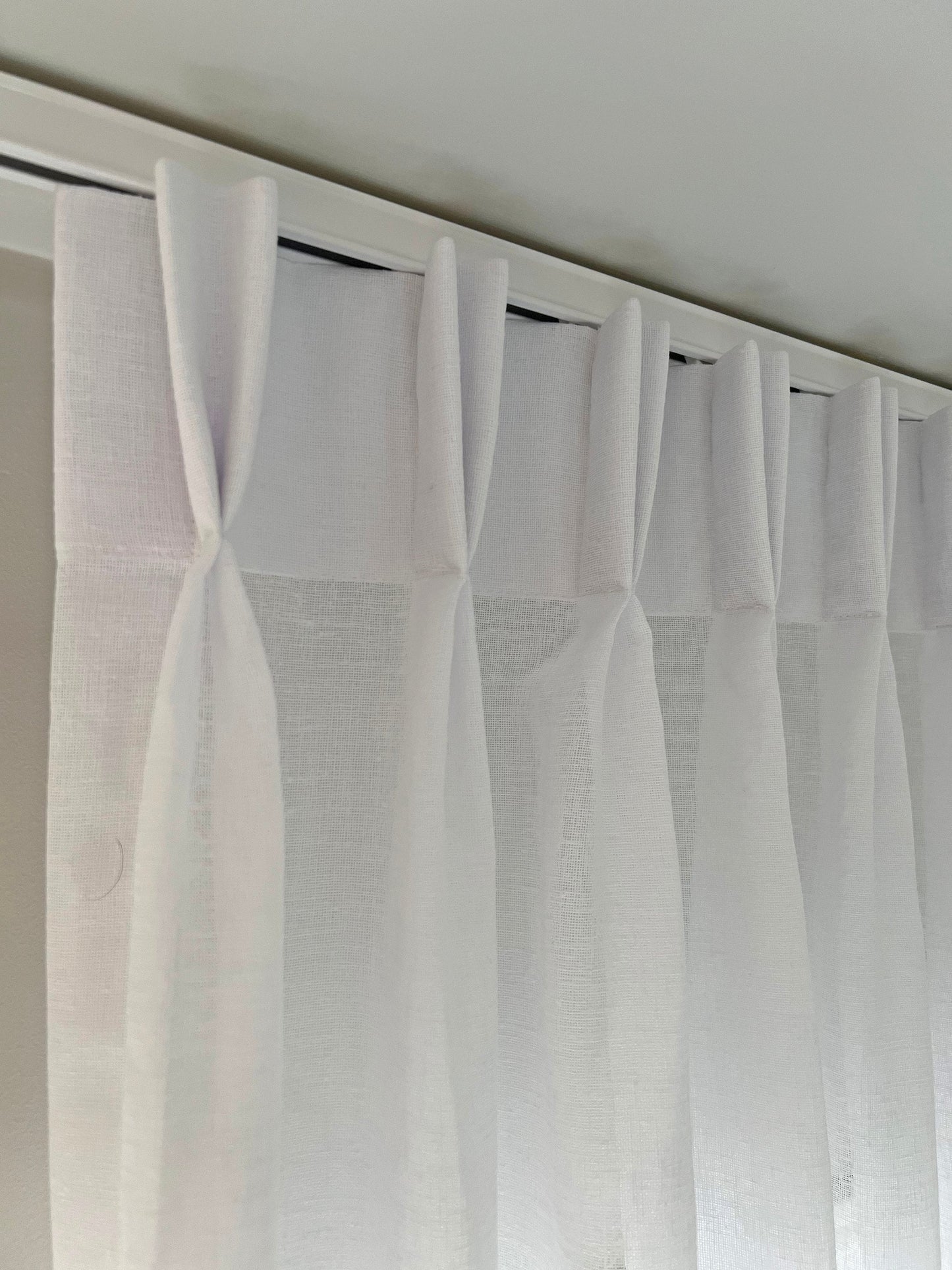 White pinch pleat drapes on traverse rod — even folds on a center open curtain track