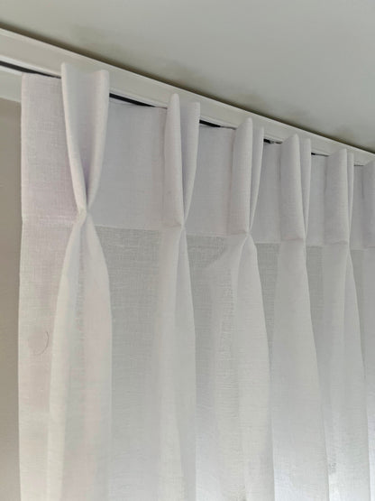 White pinch pleat drapes on traverse rod — even folds on a center open curtain track