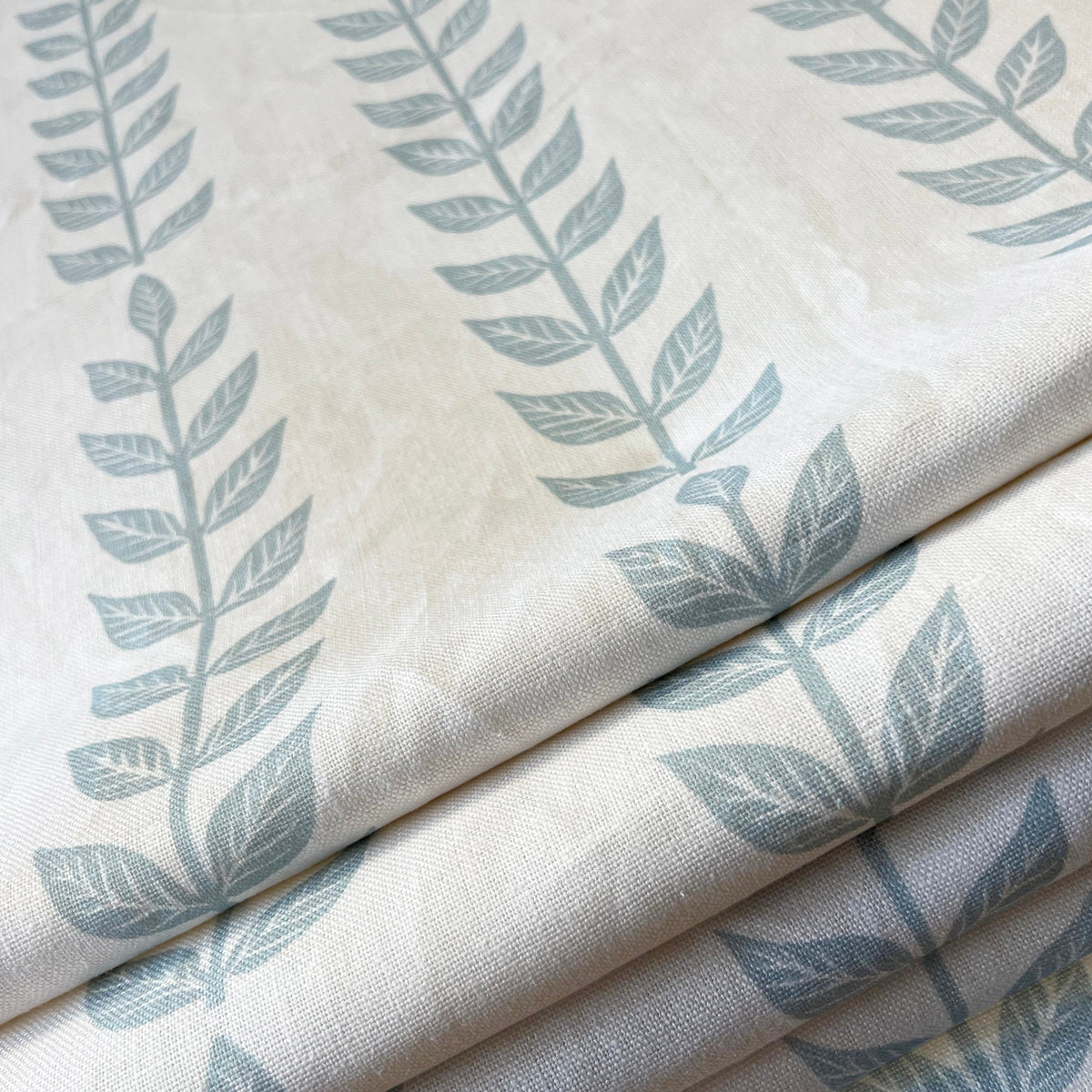 Soft blue linen shade with trailing white vine print, styled in a room