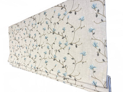 Beatrix floral relaxed Roman shade in light beige with blue and brown blossom pattern, folds dressed