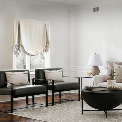 Living room with black leather armchairs and a white London tulip Roman shade with Greek key trim