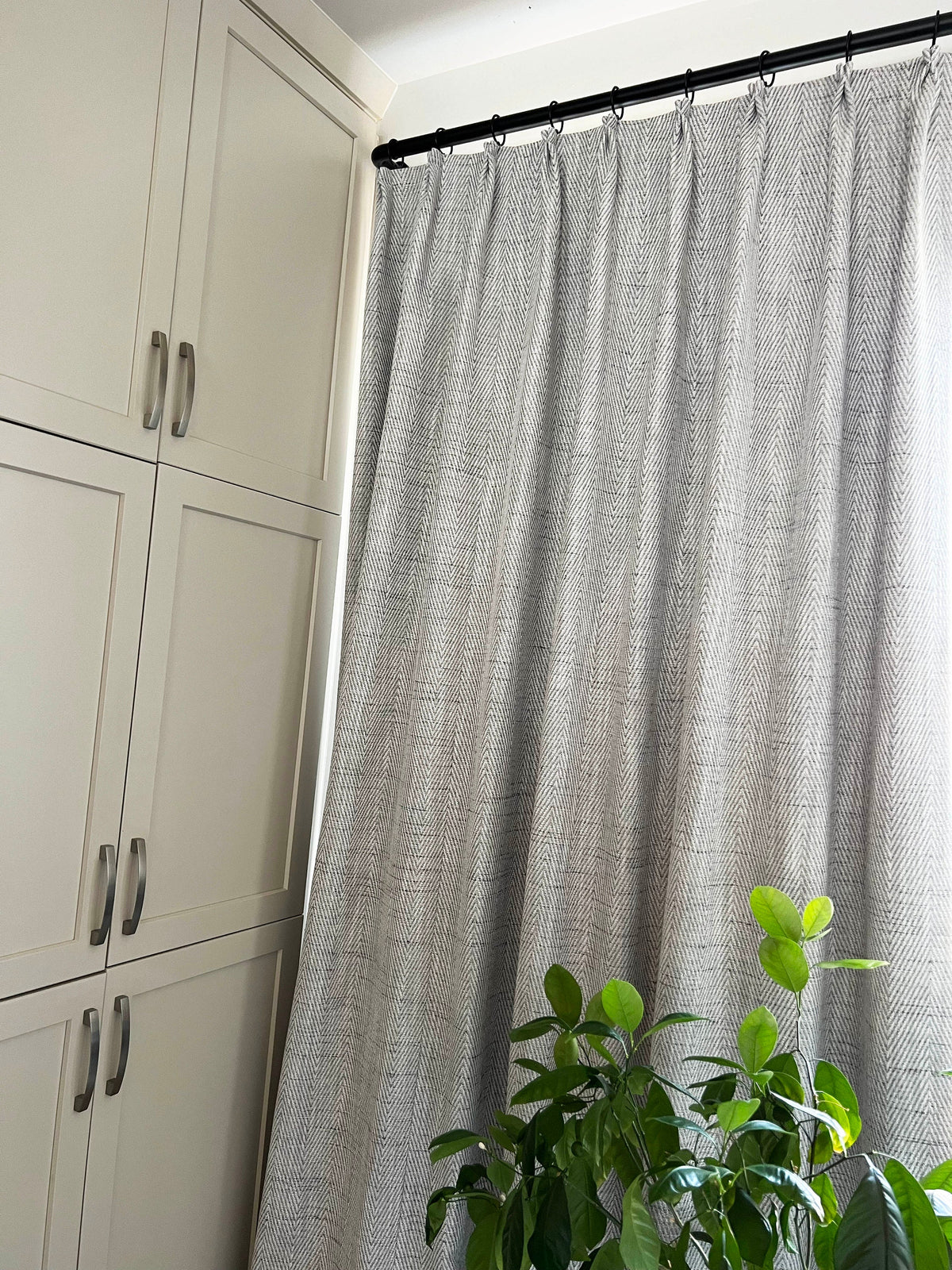 Corrie pleated panel hanging on a black curtain rod
