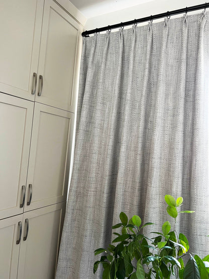 Corrie pleated panel hanging on a black curtain rod