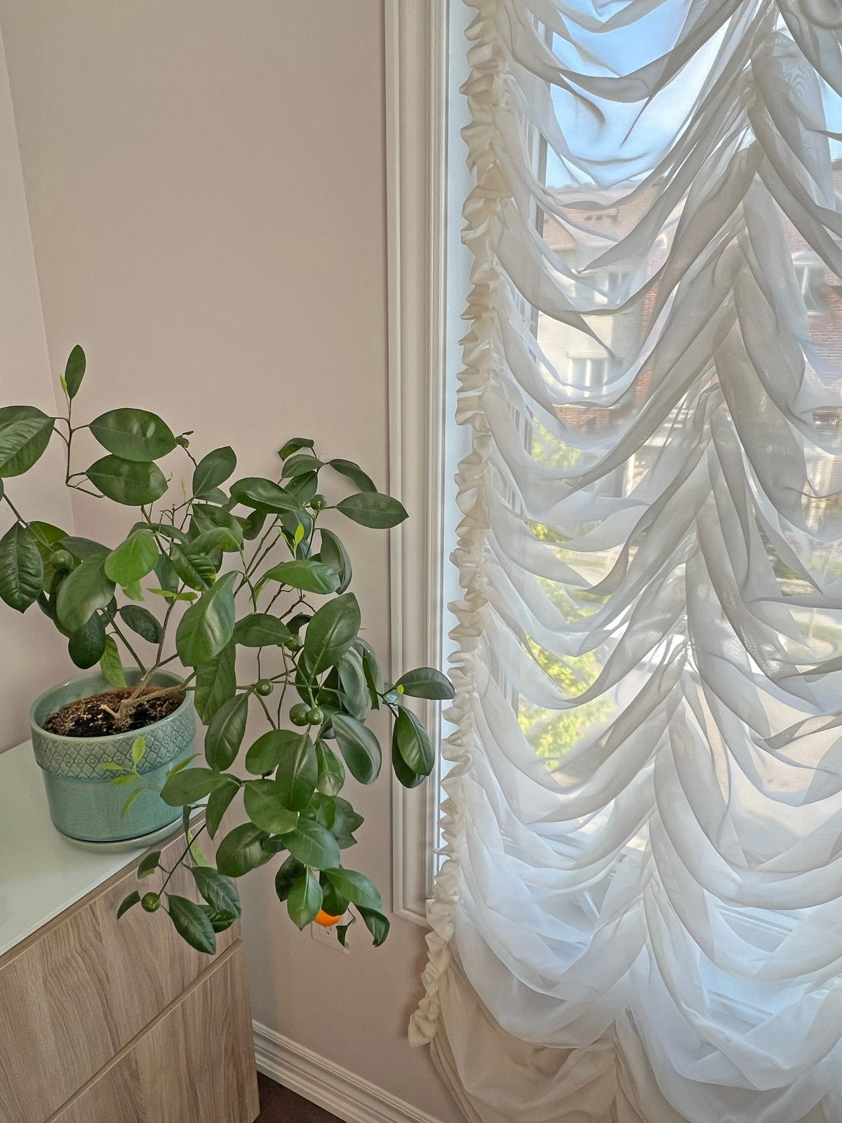 Austrian sheer shade shown at full drop in a tall window