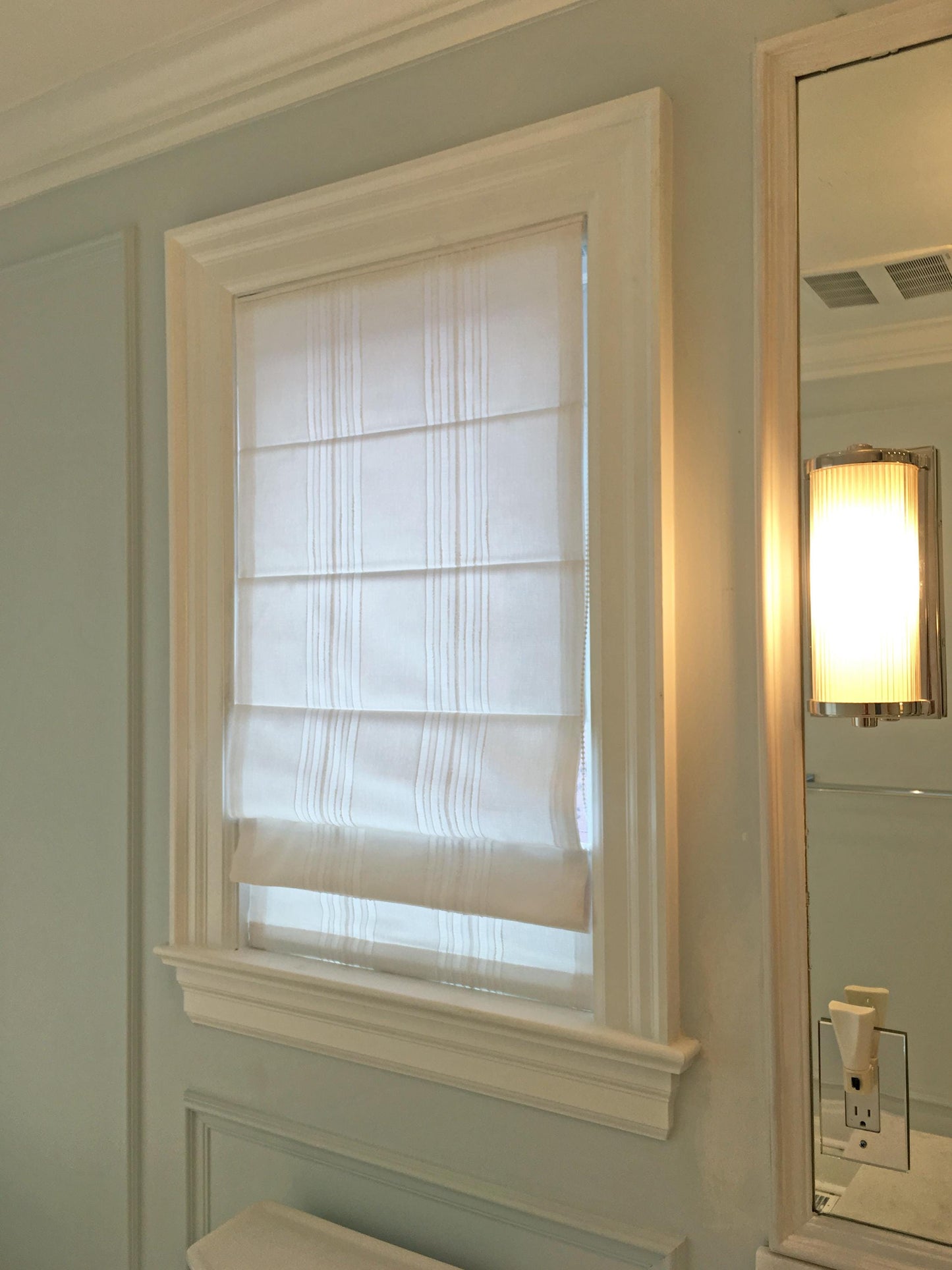 Spinello flat Roman shade in a white window frame — clean striped face