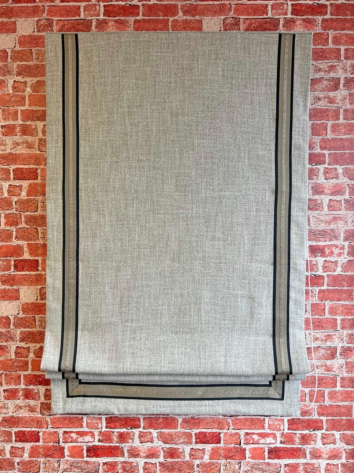 Toronto relaxed Roman shade with CE58 trim hanging in a window