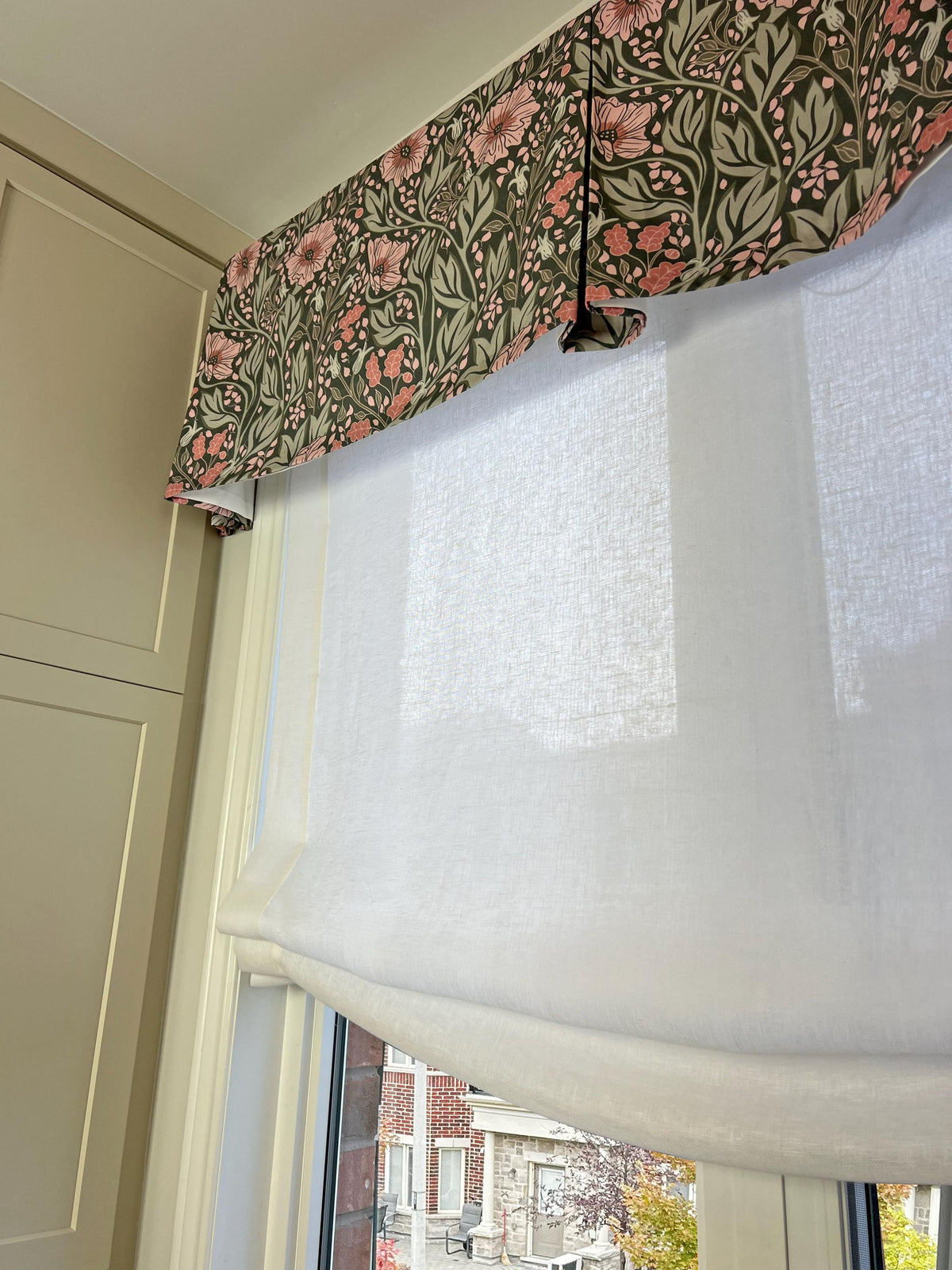 Floral pleated valance layered over a white sheer Roman shade