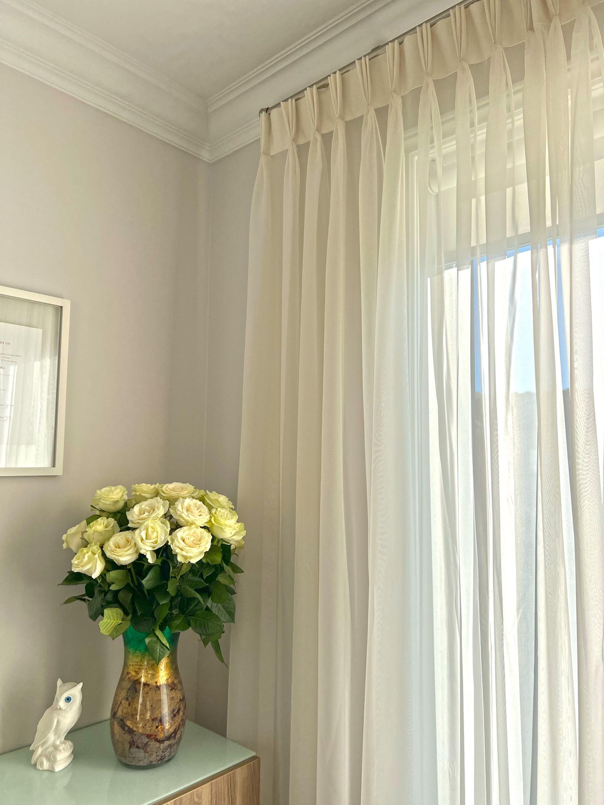 Empire voile triple pleat sheer panel at a bright window, white roses on the table — LOGANOVA