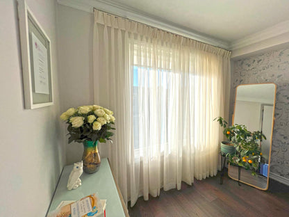 Empire voile triple pleat sheers styled with white roses in a green vase — LOGANOVA