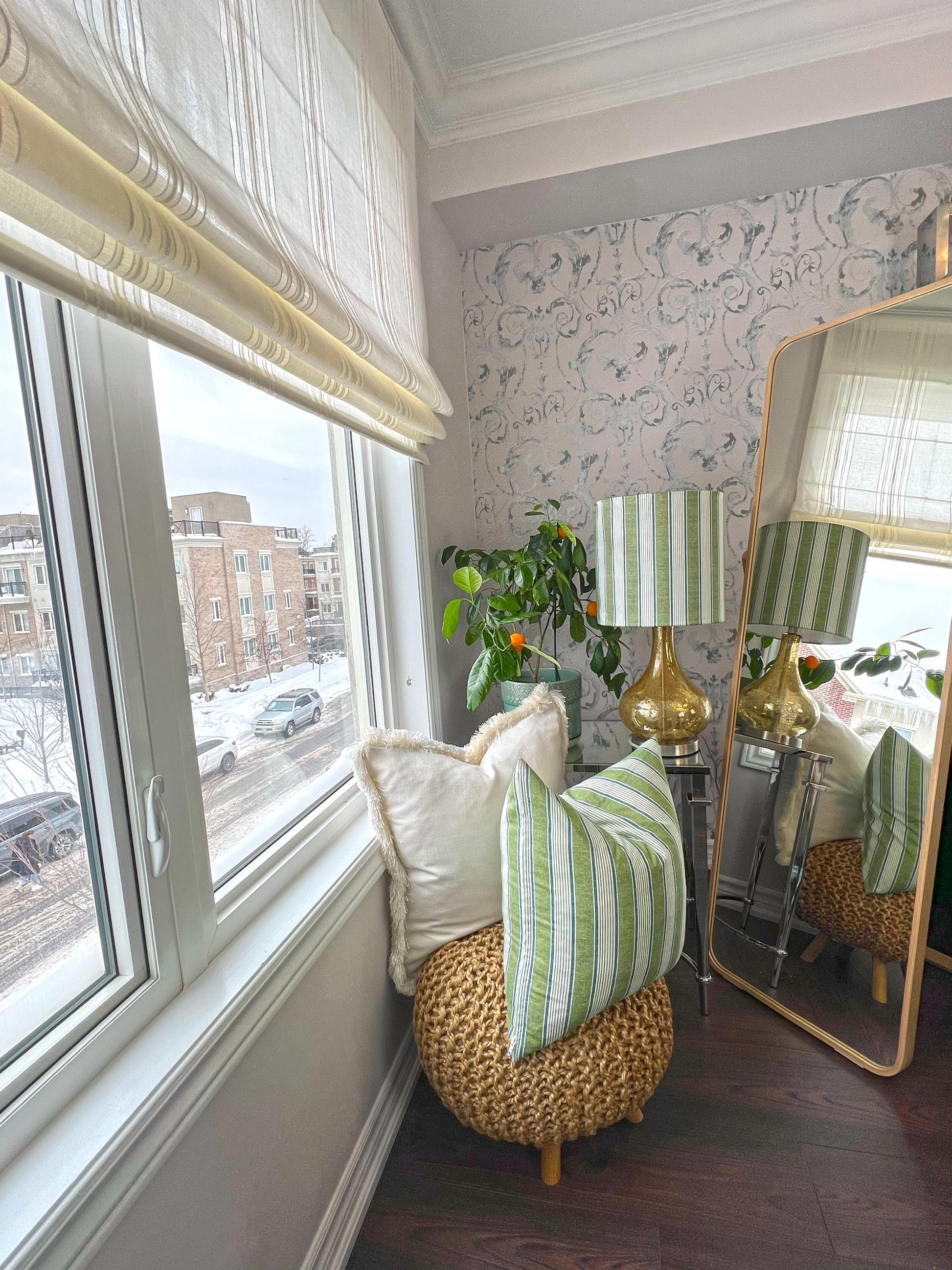 Spinello striped Roman shade in a living space with woven ottoman
