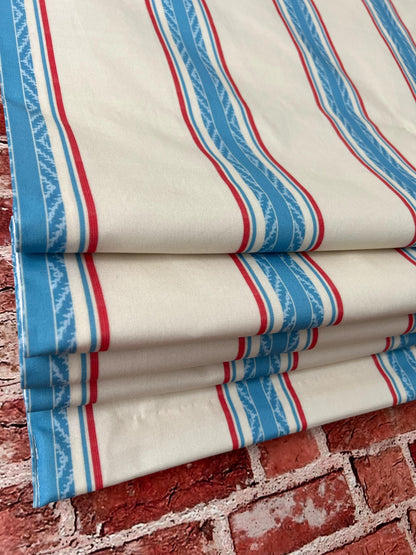 French Ticking Stripe relaxed Roman shade in a window, red and blue stripe on tea-tan ground