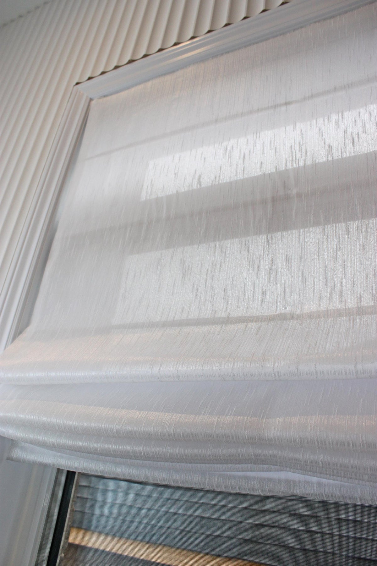 Lugano faux linen relaxed Roman shade in Lugano White, soft smile along the bottom edge