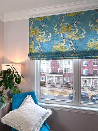 Deco Cranes Roman shade over a reading corner with teal chair — pool blue crane print