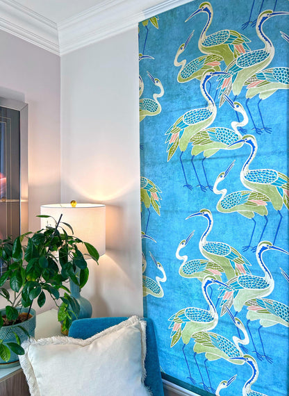 Deco Cranes Roman shade in a living space — relaxed folds, pool blue
