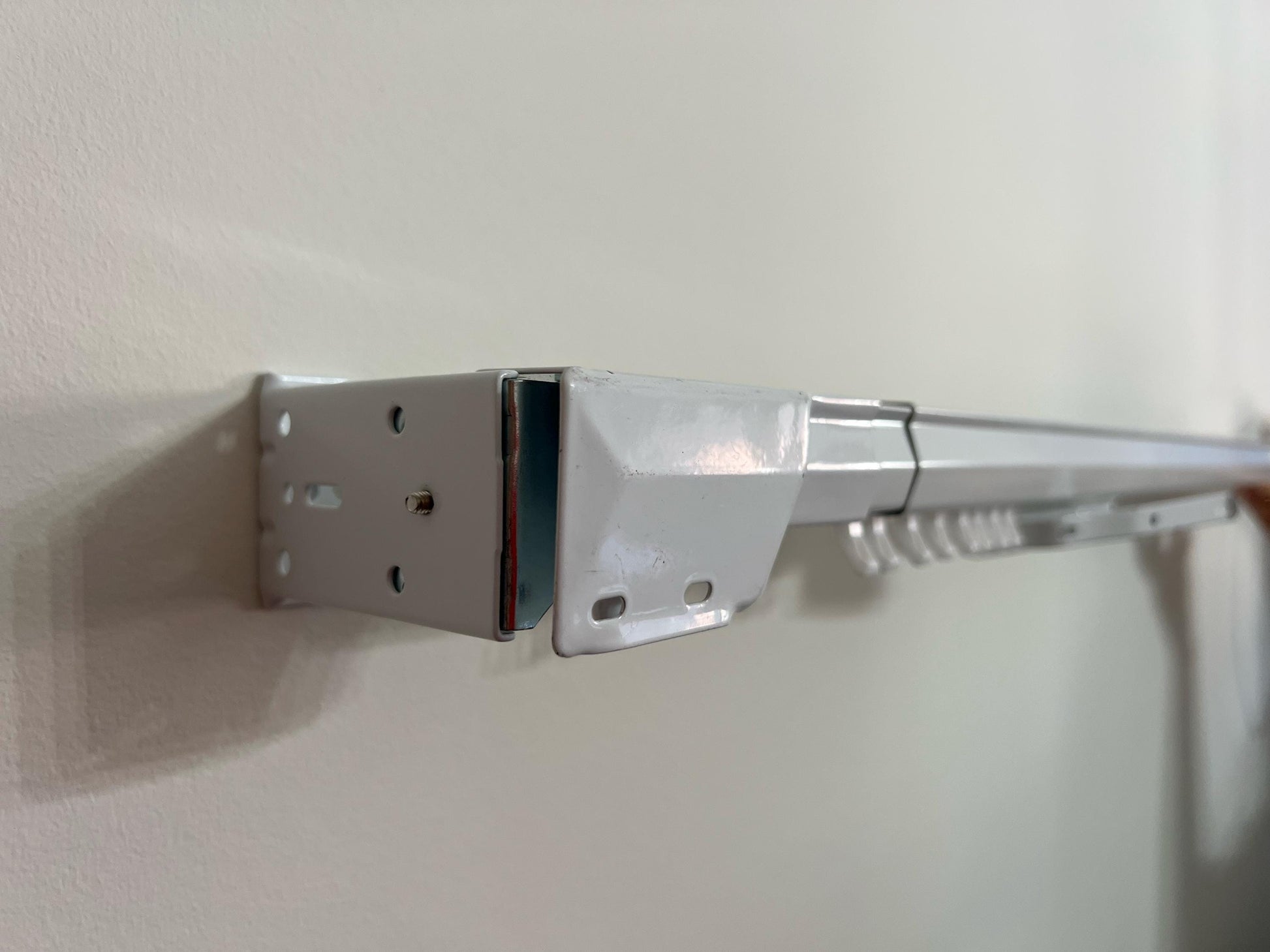 White traverse rod installed on wall with brackets — ready for pinch pleat panels