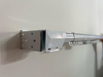 White traverse rod installed on wall with brackets — ready for pinch pleat panels
