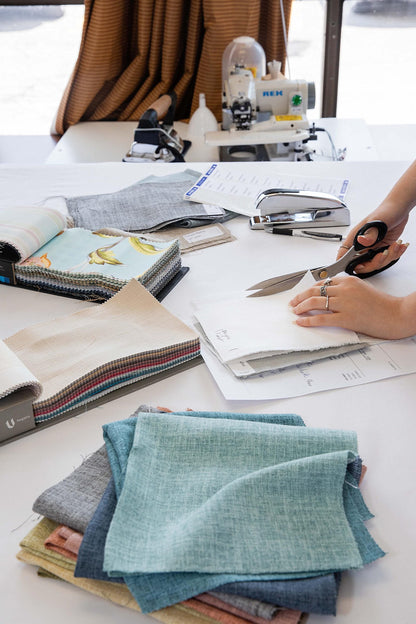 LOGANOVA Toronto studio: preparing fabric sample sets for shipping, with folded teal linen swatches and order sheets on the worktable.