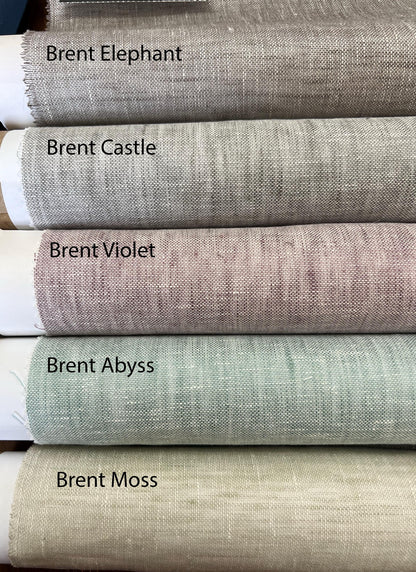 Rolled sheer linen fabrics stacked and labeled Brent Elephant, Brent Castle, Brent Violet, Brent Abyss and Brent Moss
