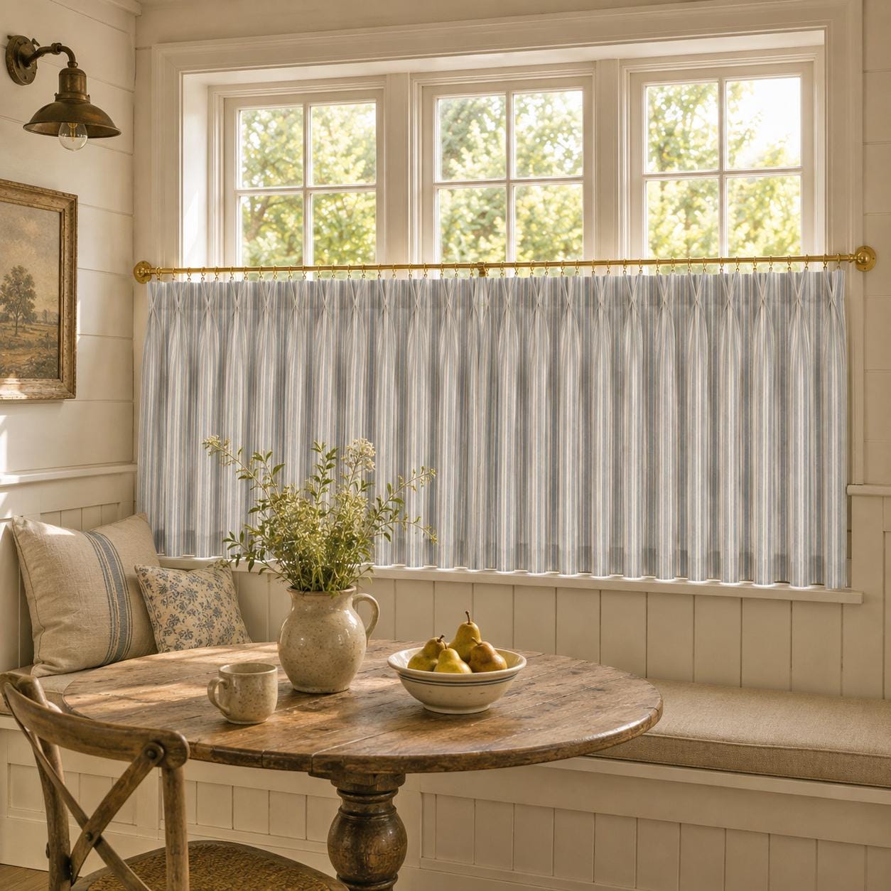 Grey ticking stripe cafe curtains on a wide window above a bench seat in a panelled room.