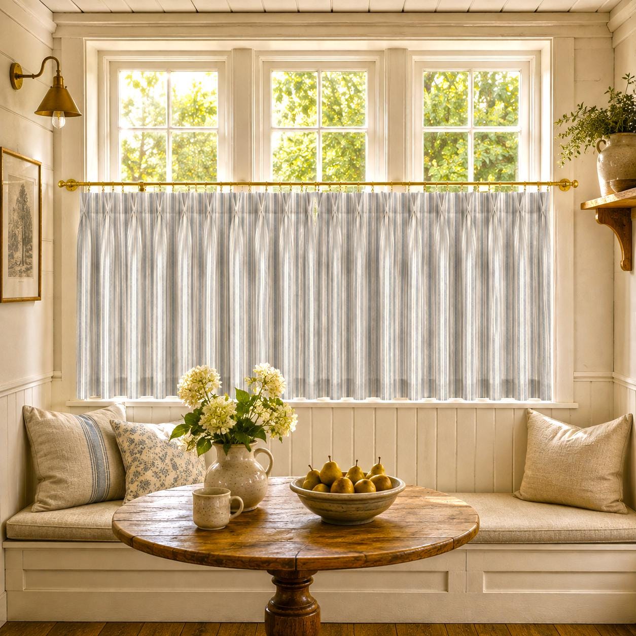 Breakfast nook window seat with striped cafe curtains, a round wooden table and yellow flowers.