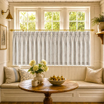 Breakfast nook window seat with striped cafe curtains, a round wooden table and yellow flowers.