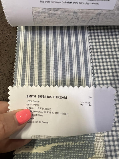 Hand holding an Alendel Smith Stream grey ticking stripe cotton swatch beside a gingham check.