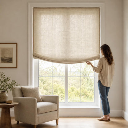 Woman lowering a natural linen European relaxed Roman shade in a bright neutral living room