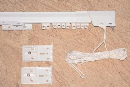 White traverse curtain rod track with mounting brackets and coiled draw cord — pinch pleat drapery hardware