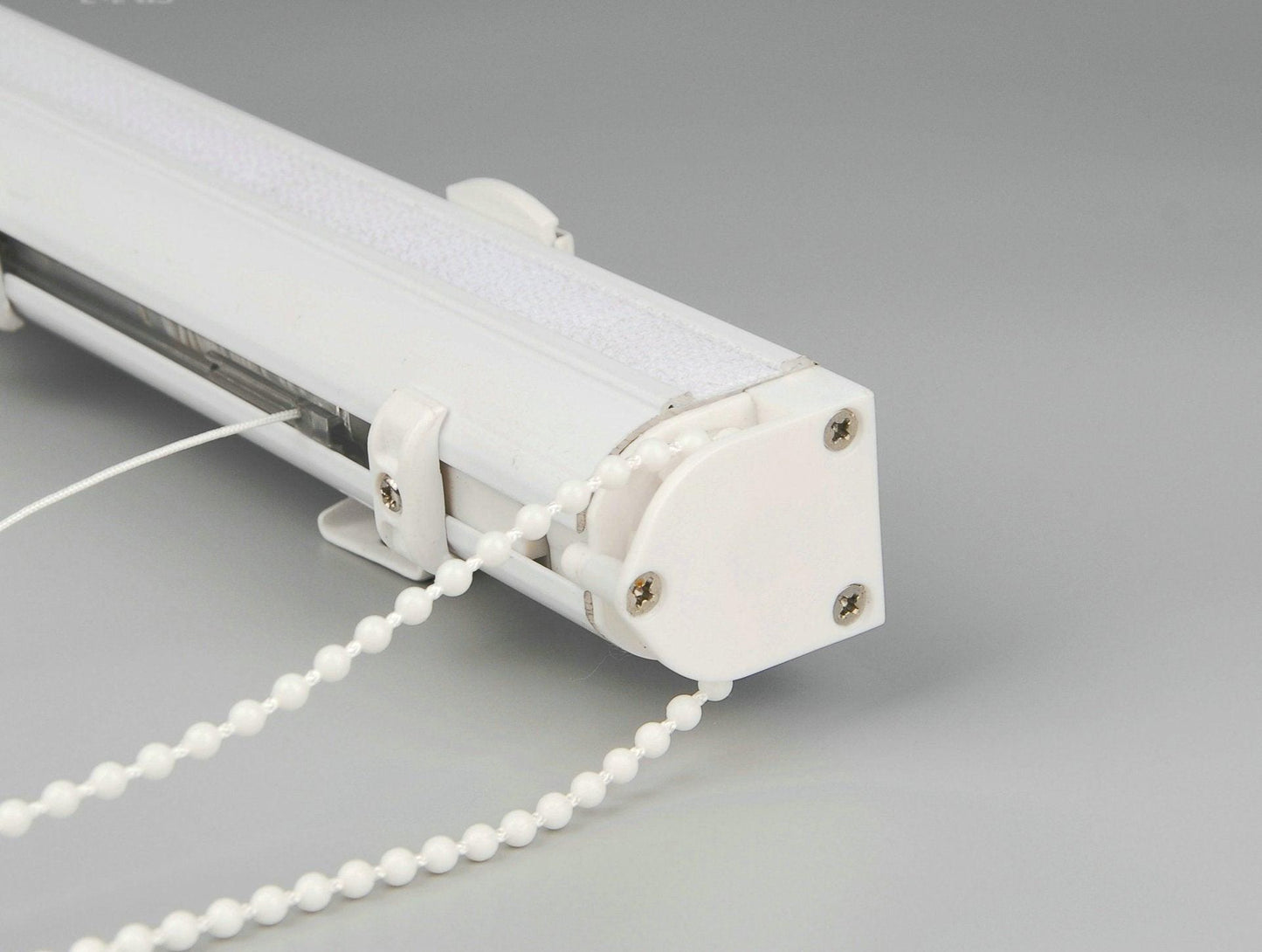 White aluminium headrail with bead chain control and mounting bracket of a custom Roman shade